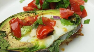 Avocado Baked Eggs are topped with tomatoes and cilantro and sprinkling of salt and pepper, the perfect low carb breakfast.