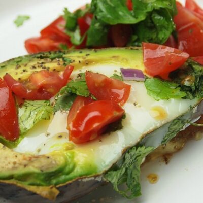 Avocado Baked Eggs are topped with tomatoes and cilantro and sprinkling of salt and pepper, the perfect low carb breakfast.