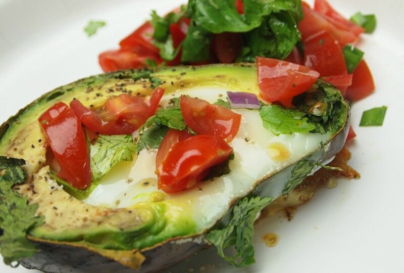 Avocado Baked Eggs are topped with tomatoes and cilantro and sprinkling of salt and pepper, the perfect low carb breakfast.