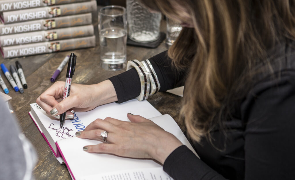 Jamie Geller's hands on book while signing it