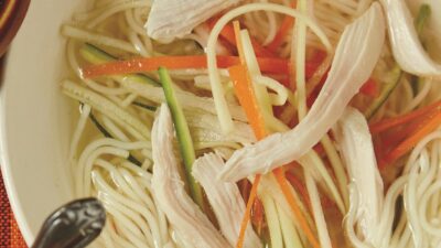 crystal clear chicken soup with julienned vegetables and angel hair