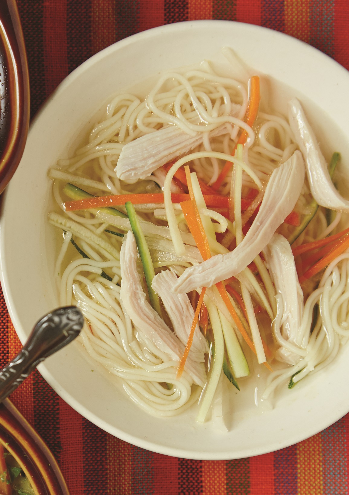 crystal clear chicken soup with julienned vegetables and angel hair