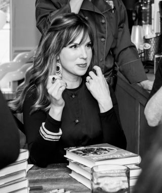 Jamie Geller smiling while signing books for fans