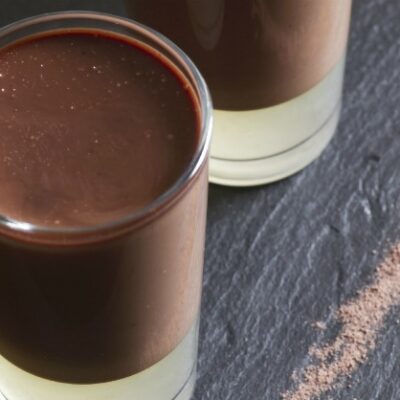 Three chocolate panna cottas with some pear syrup jelly, over a black slate